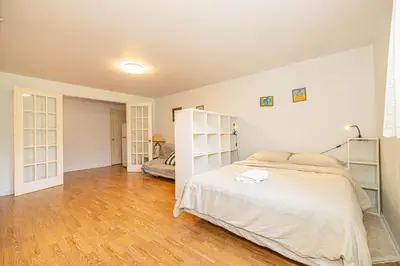 a white bedroom with a bed and a wooden floor at Cozy 1 BDR apt in MTL-E, near metro, free parking in Montréal