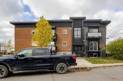 a black truck parked in front of a building at Voltaire 1 Apartement 4,5 2ch Laval, Canada in Laval