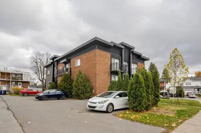 a car parked in a parking lot in front of a building at Voltaire 1 Apartement 4,5 2ch Laval, Canada in Laval