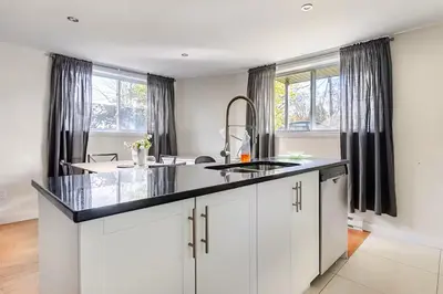 a kitchen with white cabinets and a black counter top at Voltaire 1 Apartement 4,5 2ch Laval, Canada in Laval