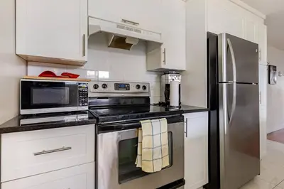 a kitchen with stainless steel appliances and white cabinets at Voltaire 1 Apartement 4,5 2ch Laval, Canada in Laval
