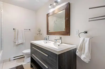 a bathroom with a sink and a mirror and a toilet at Voltaire 1 Apartement 4,5 2ch Laval, Canada in Laval