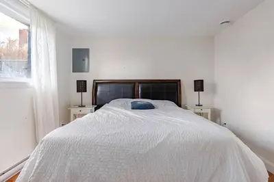a white bedroom with a large bed with two night stands at Voltaire 1 Apartement 4,5 2ch Laval, Canada in Laval