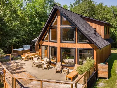a house with a deck with chairs and tables at Chalet La Dinette in Stanbridge Station