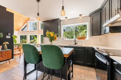 a kitchen with black cabinets and green chairs at Chalet La Dinette in Stanbridge Station