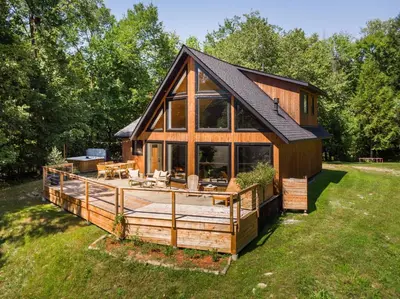a large wooden house with a large deck at Chalet La Dinette in Stanbridge Station