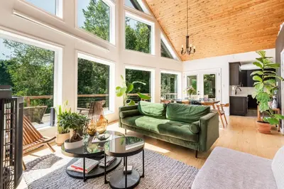 a living room with a green couch and windows at Chalet La Dinette in Stanbridge Station