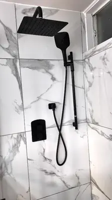 a shower head in a bathroom with marble walls at Entire Urban Cabin Retreat 3BD Terrace&Covered Parking in Terrebonne