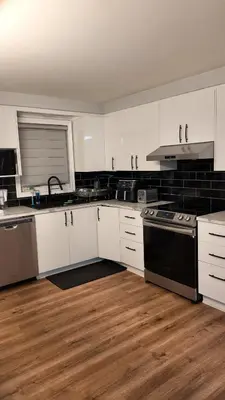 a kitchen with white cabinets and black appliances at Entire Urban Cabin Retreat 3BD Terrace&Covered Parking in Terrebonne