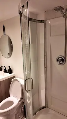 a bathroom with a shower with a toilet and a sink at Entire Urban Cabin Retreat 3BD Terrace&Covered Parking in Terrebonne