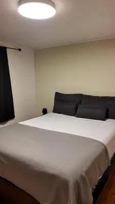 a large white bed in a room with a light at Entire Urban Cabin Retreat 3BD Terrace&Covered Parking in Terrebonne