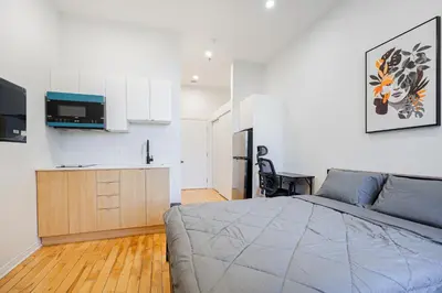 a bedroom with a large bed and a kitchen at Weekly cozy Studio For 2 Guest With Free parking in Montréal