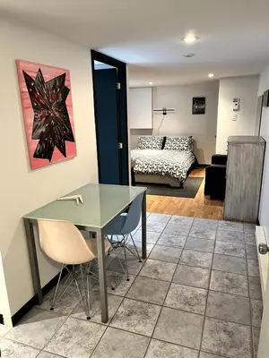 a living room with a table and a bedroom at Charmant petit studio à 15 minutes de Montréal in Longueuil