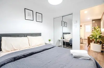 a bedroom with a large bed and a living room at Griffintown Central 2BR in Montréal