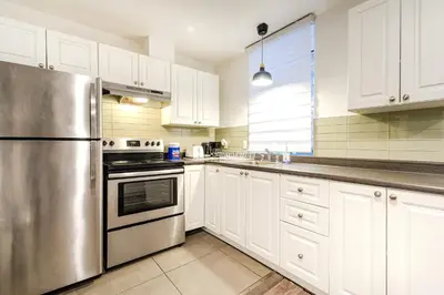 a kitchen with white cabinets and a stainless steel refrigerator at Griffintown Central 2BR in Montréal