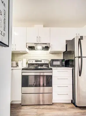 a kitchen with a stainless steel stove and white cabinets at Griffintown Cozy Haven in Montréal