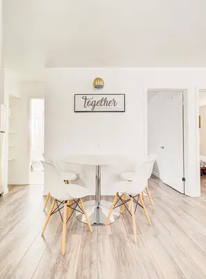 a white dining room with a table and chairs at Griffintown Cozy Haven in Montréal