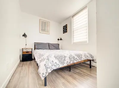a white bedroom with a bed and a window at Griffintown Cozy Haven in Montréal