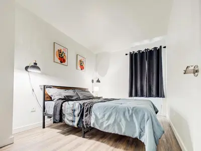 a white bedroom with a bed and a window at Griffintown Cozy Haven in Montréal