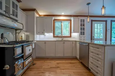 a kitchen with white cabinets and a stove top oven at Lakefront - Quai 948 in Saint Sebastien