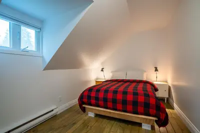 a bedroom with a bed with a red and black plaid blanket at Lakefront - Quai 948 in Saint Sebastien