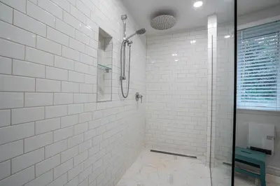 a white tiled bathroom with a glass shower at Lakefront - Quai 948 in Saint Sebastien