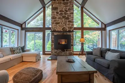 a large living room with a stone fireplace at Lakefront - Quai 948 in Saint Sebastien