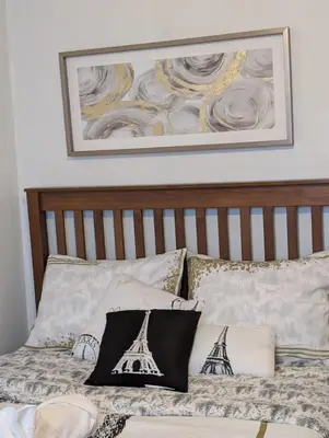 a bed with a wooden headboard with a picture on the wall at Belle chambre 2 pas Hôpital UQTR Services in Trois-Rivières