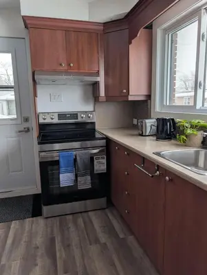 a kitchen with wooden cabinets and a stove and a sink at Belle chambre 2 pas Hôpital UQTR Services in Trois-Rivières