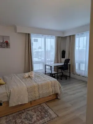 a bedroom with a bed and a table and windows at Chambre privée 5 min Université Hôpital in Trois-Rivières