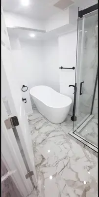 a white bathroom with a tub and a glass shower at Cute and Cozy Studio with Private Parking in Montréal
