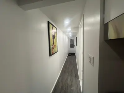 a hallway with white walls and a painting on the wall at Cute and Cozy Studio with Private Parking in Montréal