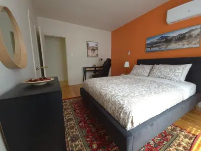 a bedroom with a large bed with an orange wall at Special Stays! Ultimate Destination for Montreal & West Island with Fast Wi-Fi in Montréal