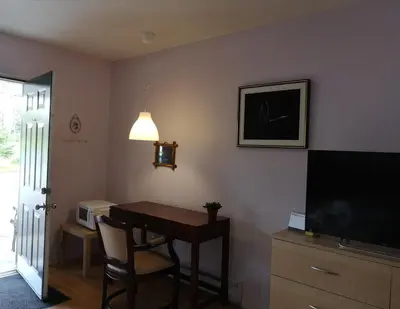 a living room with a table and a tv and a desk at Motel Alexandrin in Saint-Georges