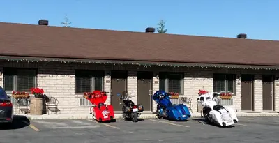 three motorcycles parked in a parking lot in front of a building at Motel Alexandrin in Saint-Georges
