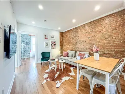 a living room with a brick wall and a table at Upscale 2BR Retreat - Parking - 2 Queen Suites in Montréal