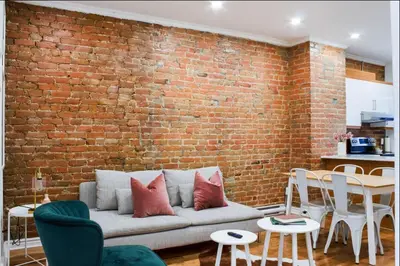 a living room with a brick wall and a couch at Upscale 2BR Retreat - Parking - 2 Queen Suites in Montréal