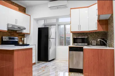 a kitchen with white cabinets and a black refrigerator at Upscale 2BR Retreat - Parking - 2 Queen Suites in Montréal