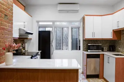a kitchen with white cabinets and a black refrigerator at Upscale 2BR Retreat - Parking - 2 Queen Suites in Montréal