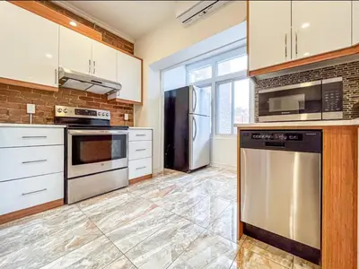 a kitchen with white cabinets and stainless steel appliances at Upscale 2BR Retreat - Parking - 2 Queen Suites in Montréal