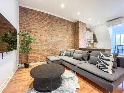 a living room with a couch and a brick wall at Modern 2BR Haven - Prime Location in Montréal