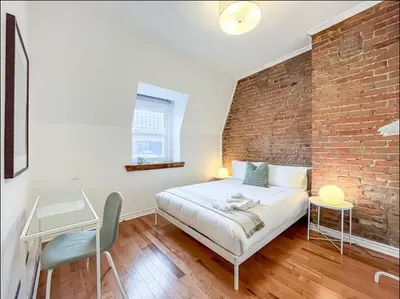 a bedroom with a brick wall and a bed at Modern 2BR Haven - Prime Location in Montréal
