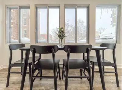 a dining room table with four chairs and windows at Modern 2BR Haven - Prime Location in Montréal