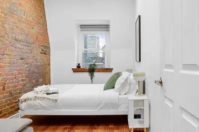 a bedroom with a white bed and a brick wall at Modern 2BR Haven - Prime Location in Montréal