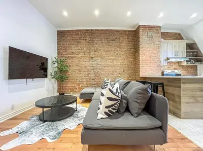 a living room with a couch and a brick wall at Modern 2BR Haven - Prime Location in Montréal