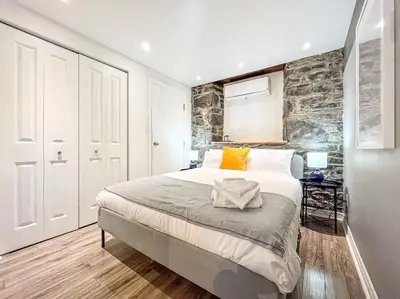 a bedroom with a large bed and a stone wall at Elegant 1BR Suite - Washer & Dryer - Prime Location in Montréal