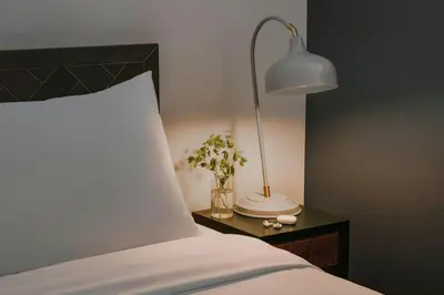 a bed with a lamp and a vase of flowers on a table at The Alexander Hotel - Old Montreal in Montréal