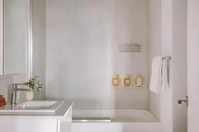 a white bathroom with a sink and a mirror at The Alexander Hotel - Old Montreal in Montréal