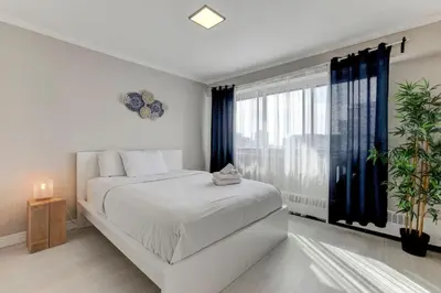 a bedroom with a white bed and a large window at Refined Downtown 1BR Suite - Luxury Comfort in Montréal