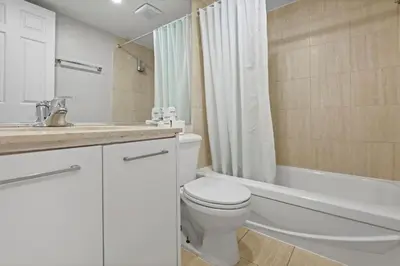 a white bathroom with a toilet and a bath tub at Luxury Downtown 1BR Residence - Urban Comfort in Montréal